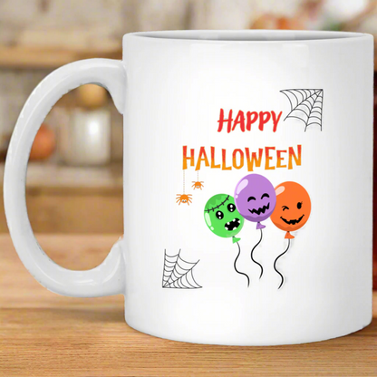 A white ceramic mug with a 'Happy Halloween' text and decorations featuring a spider, pumpkin, and balloon design.